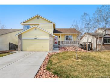 Charming yellow two-story home featuring an attached garage and inviting front porch at 13463 Quivas St, Westminster, CO 80234