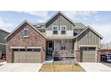 Charming two-story home featuring a stone facade, two-car garage, and inviting front porch at 12965 Grassland St, Longmont, CO 80504