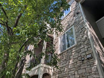 Low angle view of stone exterior of home and tree with branches in the foreground at 7369 S Alkire St # 203, Littleton, CO 80127