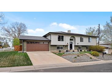 Split level home with two car garage, muted colors, landscaping, and driveway at 11165 W 58Th Ave, Arvada, CO 80002
