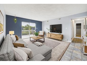 Bright living room with neutral carpet, blue accent wall, and sliding glass doors to a balcony at 190 E Highline Cir # 302, Centennial, CO 80122
