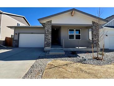 Charming single-story home featuring stone accents, a covered porch, and a well-maintained front yard at 230 Lark Sparrow Way, Bennett, CO 80102