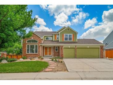 Inviting two-story home with a brick facade, lush lawn, and a three car attached garage at 2882 Signal Creek Dr, Thornton, CO 80241