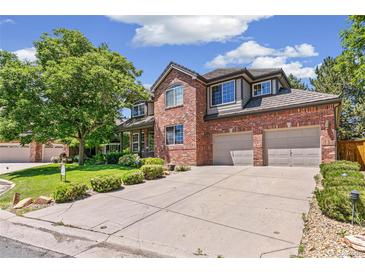 Charming brick two-story home with a manicured lawn and a two-car garage on a sunny day at 6429 S Jamaica Cir, Englewood, CO 80111