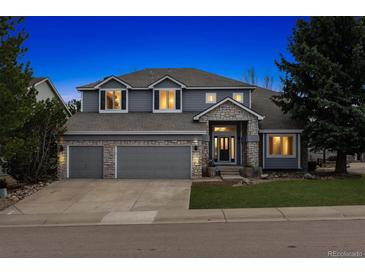 Stunning two-story home with stone accents, three-car garage, and beautifully landscaped front yard at dusk at 598 Stonemont Dr, Castle Pines, CO 80108