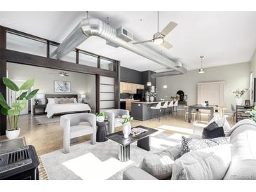 Bright, open floor plan with modern decor, kitchen island, and visible bedroom enhance this inviting living space at 2501 15Th St # 2C, Denver, CO 80211