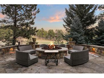 Stone patio boasts a cozy fire pit with comfortable wicker seating, perfect for outdoor gatherings at 77 Comstock Pl, Castle Rock, CO 80108