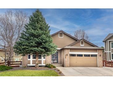 Charming exterior elevation features brick and siding, a mature tree, and attached two-car garage at 6118 Salvia Ct, Arvada, CO 80403