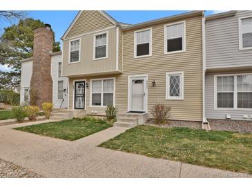 Charming townhome featuring a well-maintained lawn, neutral siding, and inviting entryway at 8879 W Floyd Ave, Lakewood, CO 80227