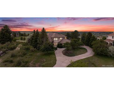 Charming two-story home with mature trees and a circular driveway at sunset at 5855 Saddle Creek Trl, Parker, CO 80134