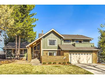 Inviting two-story home with a brick and siding facade, complemented by a well-manicured lawn and mature trees at 8159 Lodgepole Trl, Lone Tree, CO 80124