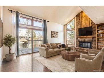 Inviting living room features a cozy fireplace, deck access, and large windows providing ample natural light at 8159 Lodgepole Trl, Lone Tree, CO 80124