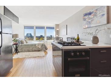 Open concept living area featuring hardwood floors, large windows with city views, and a modern kitchen at 789 N Clarkson St # 906, Denver, CO 80218