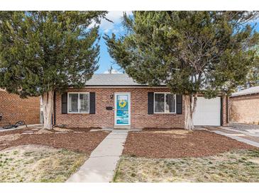 Charming brick home featuring a blue door with a wreath, a well-maintained yard, and lush greenery at 1575 Verbena St, Denver, CO 80220
