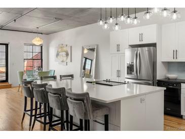 Modern kitchen features a large island, stainless steel appliances, and sleek white cabinetry at 1499 Blake St # 3M, Denver, CO 80202