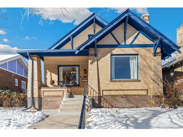 Charming brick home featuring blue trim, a cozy front porch, and freshly shoveled walkway at 2663 King St, Denver, CO 80211