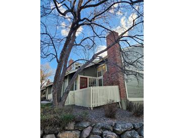 Charming home featuring a brick chimney, inviting red door, and white picket fence at 2008 S Hannibal St # A, Aurora, CO 80013