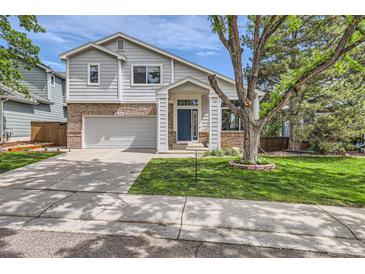 Charming two-story home boasts a brick facade, attached garage, and a welcoming front porch with a blue front door at 5260 Morning Glory Pl, Highlands Ranch, CO 80130