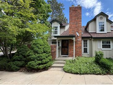 Charming home featuring a brick chimney, dormer windows, and lush landscaping for added curb appeal at 971 S Evanston Cir, Aurora, CO 80012