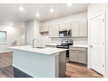Bright kitchen with an island, modern appliances, and gray cabinetry at 18998 E 94Th Pl, Commerce City, CO 80022
