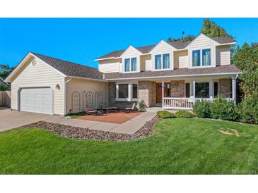 Charming two-story home with a well-manicured lawn, brick accents, and an inviting front porch seating area at 8000 S Williams Way, Centennial, CO 80122