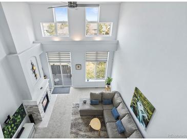 Bright living room boasts soaring ceilings, fireplace, oversized windows, and a comfortable sectional sofa at 3425 W 111Th Loop # B, Westminster, CO 80031