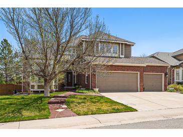 Charming two-story home featuring a brick facade and a three-car garage, complemented by a well-manicured lawn at 10305 Charissglen Cir, Highlands Ranch, CO 80126