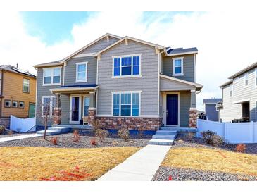 Inviting townhome featuring stone accents, covered front porch and concrete walkway at 5154 Bittercress Rd, Brighton, CO 80640