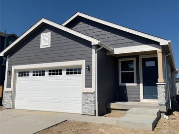 Charming gray house boasts a white garage door, stone accents, and a covered entryway with a dark blue door at 9085 Rifle St, Commerce City, CO 80022