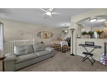 Open-concept living room featuring a comfortable sofa and seamless access to the dining area and staircase at 479 Black Feather Loop # 311, Castle Rock, CO 80104