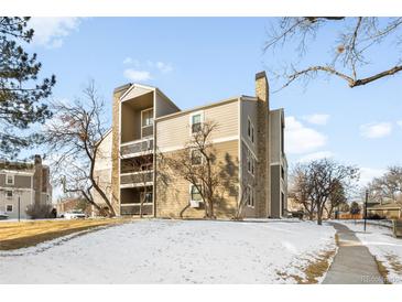 Inviting condo building with balconies and a stone chimney on a snow-covered lawn at 4896 S Dudley St # 6-5, Littleton, CO 80123