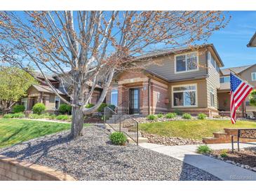 Inviting townhome with a charming brick facade, well-maintained landscaping, and an American flag on display at 6406 Silver Mesa Dr # F, Highlands Ranch, CO 80130
