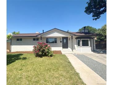 Charming single-story home featuring a manicured lawn, brick facade, and inviting front porch at 8239 Nola Dr, Denver, CO 80221