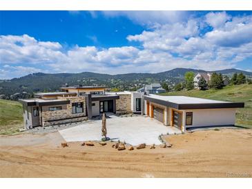 Stunning contemporary home with stone accents and a large concrete driveway, set against a scenic mountain backdrop at 545 Strada Rossa Rd, Golden, CO 80401