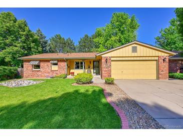 Charming brick and yellow home with a well-manicured lawn and mature trees at 12348 Elizabeth Ct, Thornton, CO 80241