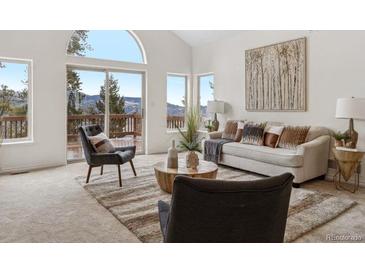 Bright living room with large windows, stylish furniture, and beautiful mountain views and modern decor at 1580 Santa Fe Mountain Rd, Evergreen, CO 80439