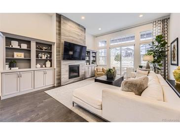 Bright living room with fireplace, built-ins, and large windows offering community views at 7214 S Shady Grove Ct, Aurora, CO 80016