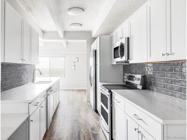 Bright kitchen featuring stainless steel appliances, gray subway tile backsplash, and white cabinets at 7877 E Mississippi Ave # 901, Denver, CO 80247