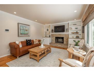 Living room with a fireplace, built-in shelves, and hardwood floors at 6941 S Poplar Way, Centennial, CO 80112