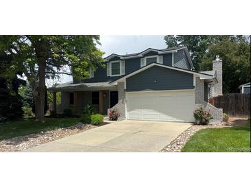 Two-story home featuring gray siding, stone accents, mature trees, and a driveway leading to an attached two-car garage at 5914 S Kearney St, Centennial, CO 80111