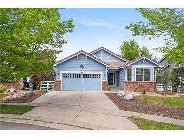 Charming blue home featuring a two-car garage, brick accents, and a well-maintained front yard at 1118 S Duquesne Cir, Aurora, CO 80018