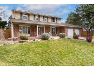 Charming two-story home with brick facade, covered front porch, and well-manicured lawn at 8510 Independence Way, Arvada, CO 80005