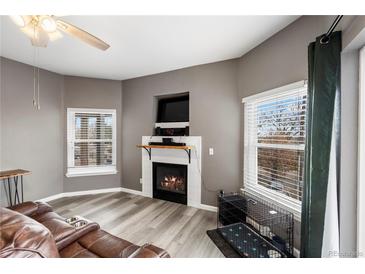 Cozy living room features a fireplace with mantel and plenty of natural light from the windows at 2428 W 82Nd Pl # 2D, Westminster, CO 80031