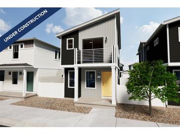 Modern two-story home featuring black and gray siding, white trim, balcony, and a bright yellow door at 13031 E 103Rd Pl, Commerce City, CO 80022