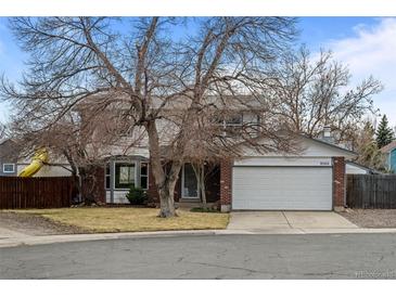 Charming two-story home with brick facade, mature trees, and a two-car garage in a residential neighborhood at 9560 W 104Th Ave, Broomfield, CO 80021