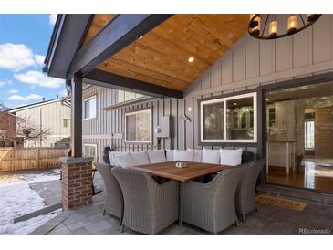 Inviting outdoor space with covered patio, wicker furniture, and seamless indoor-outdoor flow at 7233 S Harrison Way, Centennial, CO 80122