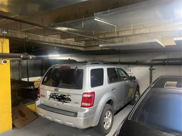 Indoor parking garage showing reserved parking space with silver Ford Escape parked inside, a convenient amenity for residents at 1020 15Th St # Pk138, Denver, CO 80202