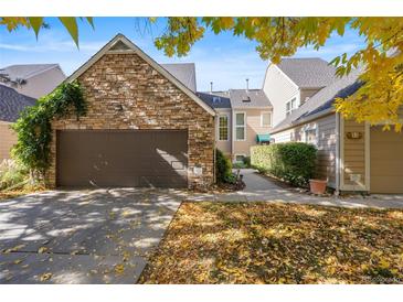 Charming townhouse with a stone facade, two-car garage, and a beautifully maintained front yard with mature trees at 10000 E Yale Ave # 41, Denver, CO 80231