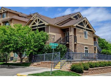 Attractive condo building featuring stone accents, brown siding, and well-maintained landscaping with a blue sky backdrop at 8726 S Kline St # A204, Littleton, CO 80127