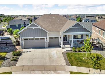 Gray two-story home featuring a three car garage and covered porch at 23913 E Swallow Cir, Aurora, CO 80016